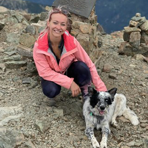 Professor Paton squatting down with a dog on a mountainside.