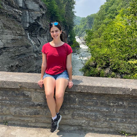 Rebecca sitting on a rock wall facing the camera with a gorge in the background.