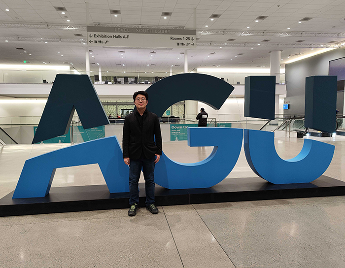 Shi standing in front of a sign.