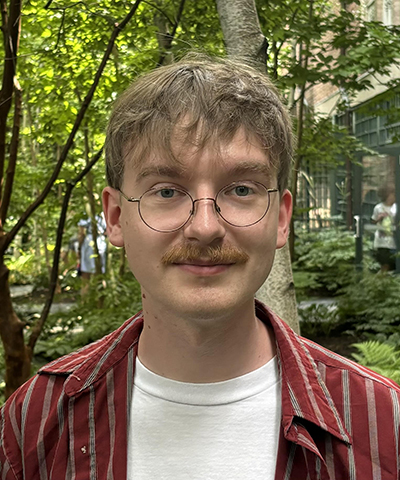 A headshot of Harrison smiling at the camera.