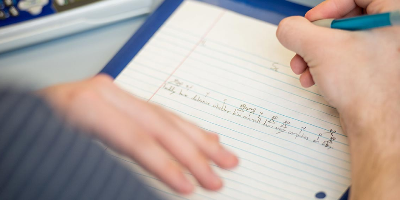 A close up of a hand writing in a notebook.