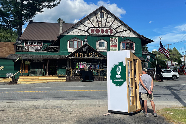 A booth on a street with a person standing beside it.