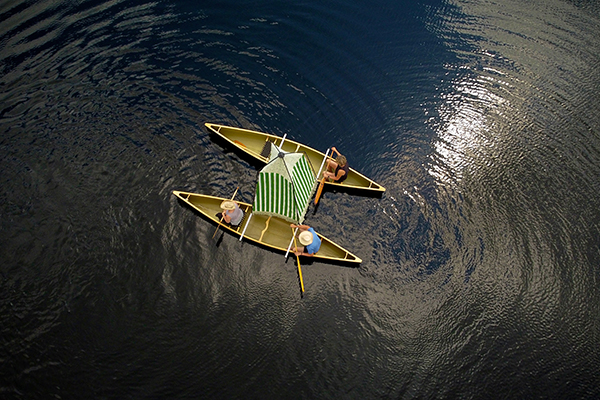 Two crew boats with one person each on a river seen from above.
