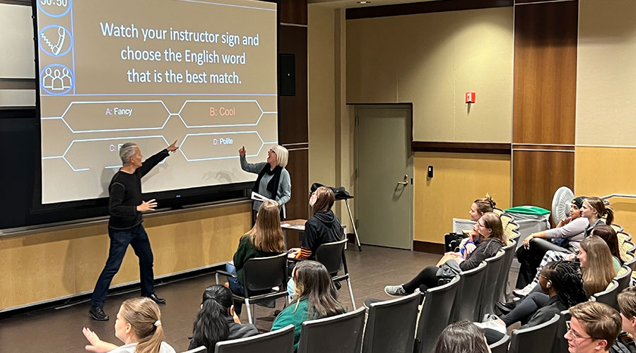 A speaker pointing at a screen.