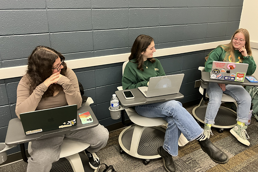 Three students sitting in desks in a classroom.