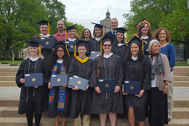 A group smiling at the camera while wearing caps and gowns.
