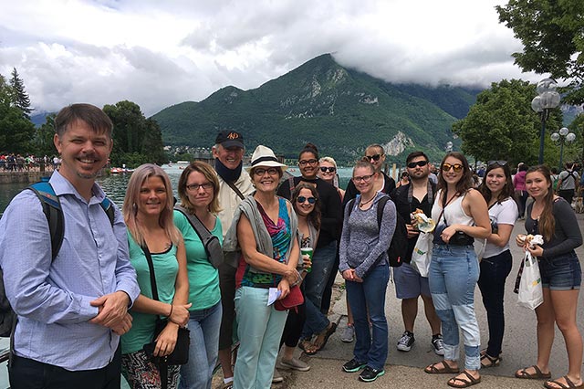 A group poses with mountains and clouds in the background.