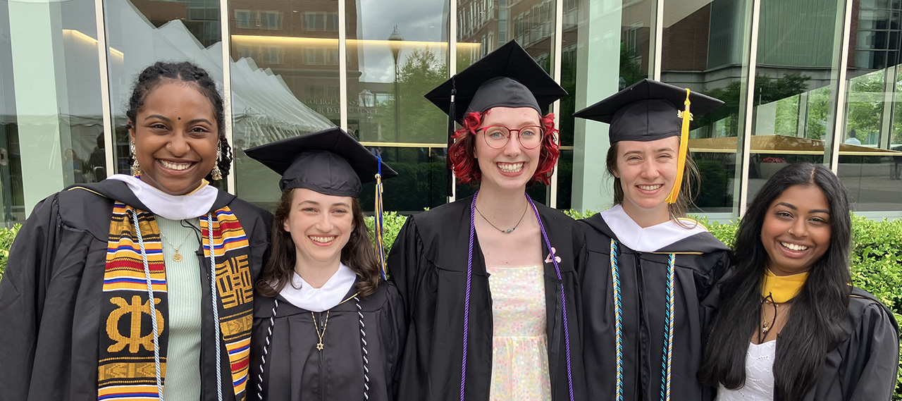 A group of ASL graduates from the class of 2023 posing for a photo on the Hajim Quad with their diplomas.