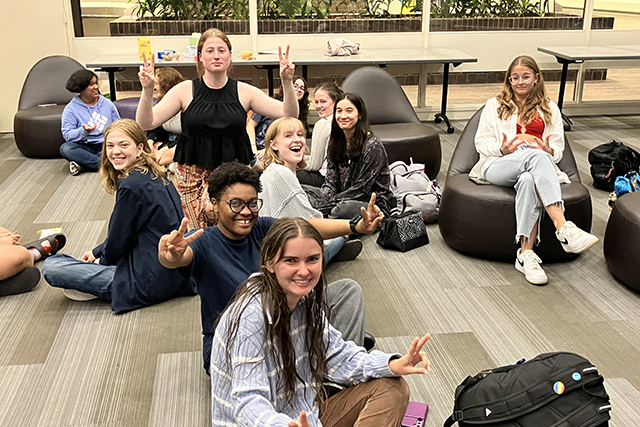 A group of smiling students sitting on the floor.