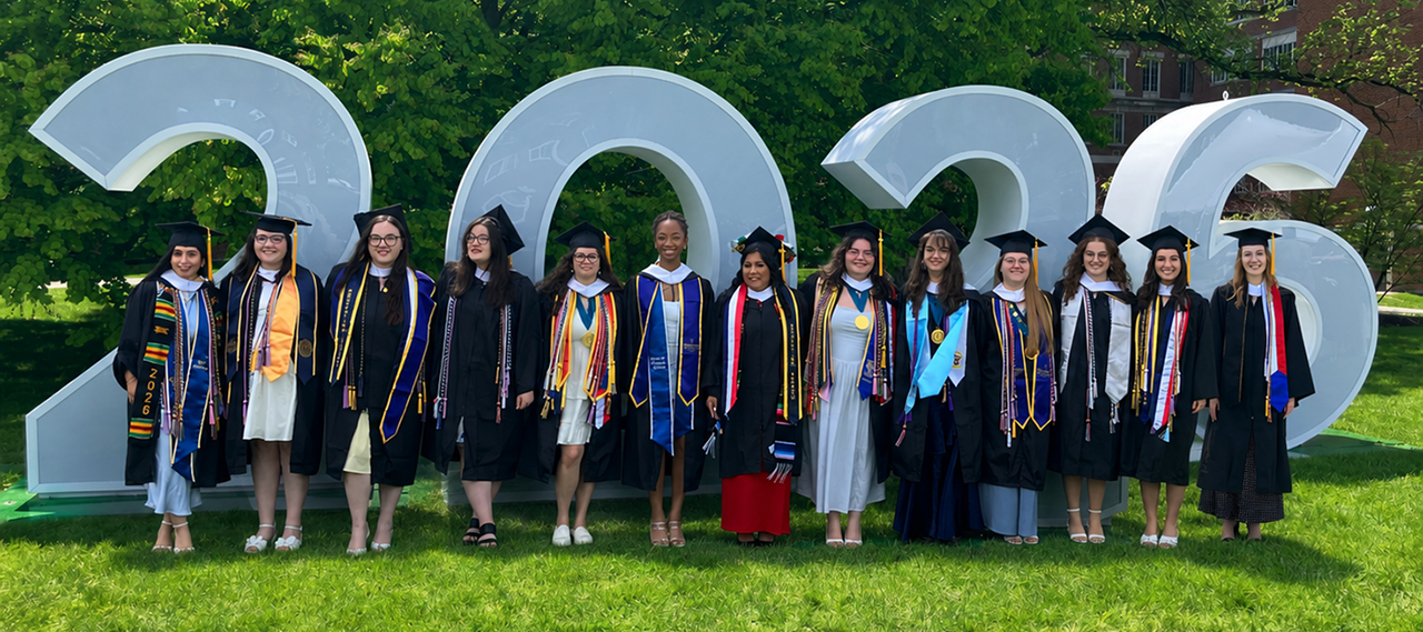 A group of ASL graduates from the class of 2026 pose in front of large numbers.