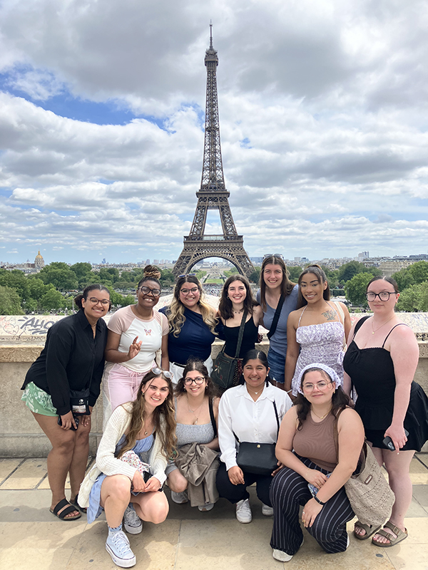 A group of students posing in front of the Eiffel Tower in Paris, France.