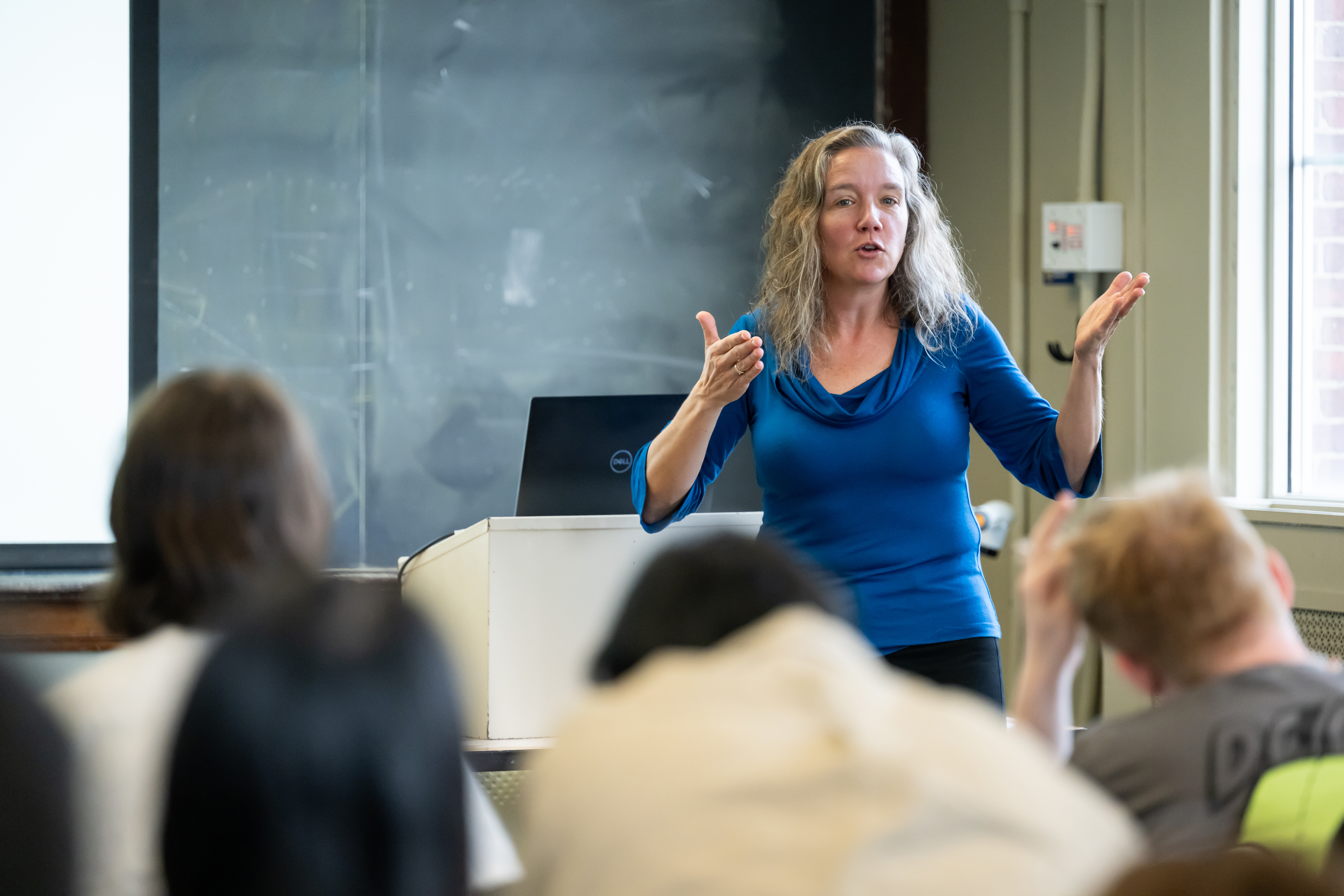 A close up of a faculty person in a classroom with blurred students in the foreground.