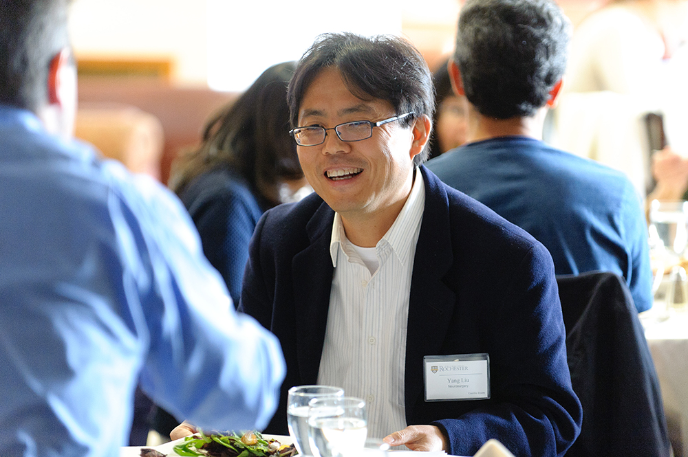 A faculty person smiling at someone across a table.