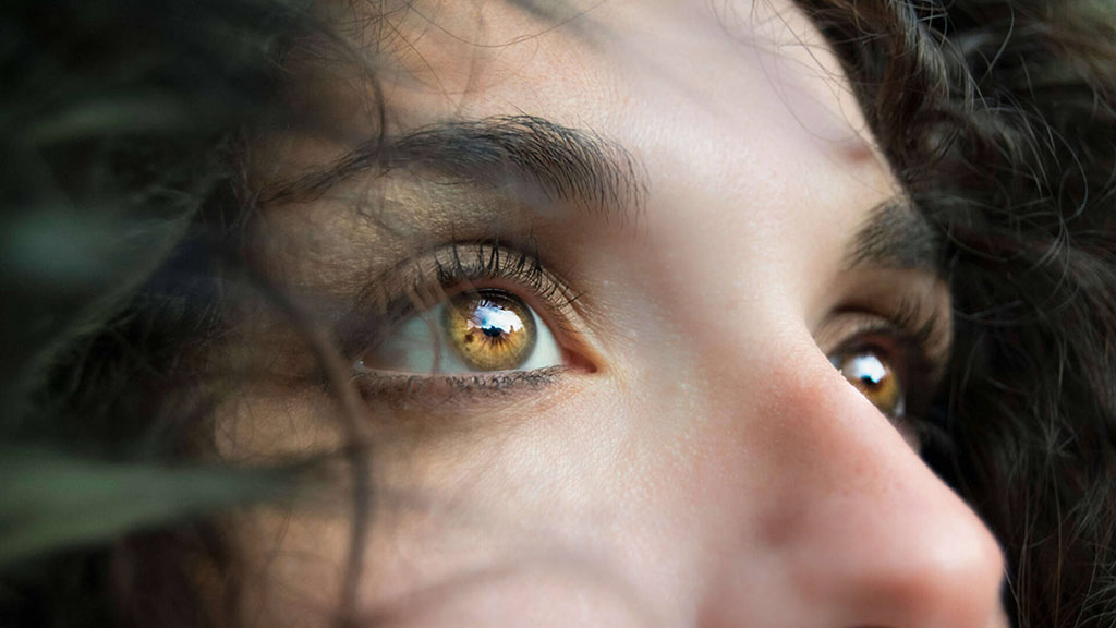 Close up of a woman's eyes and mid-face looking off camera to illustrate why eye blinking is important in humans.