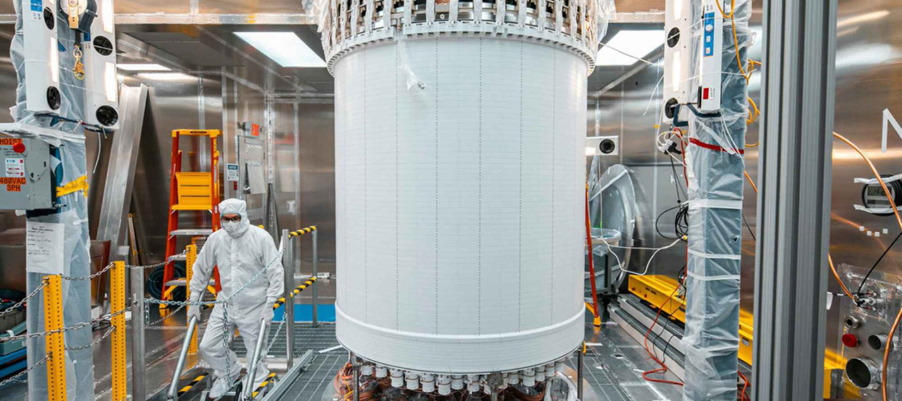 A person in a cleanroom suit walks past the LUX-ZEPLIN central detector, used to detect weakly interacting massive particles, known as WIMPs.