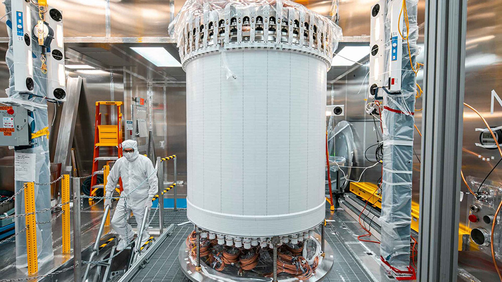 A person in a cleanroom suit walks past the LUX-ZEPLIN central detector, used to detect weakly interacting massive particles, known as WIMPs.