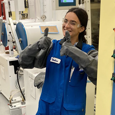 Medina Afandiyeva in a lab coat and gloves with two thumbs up.