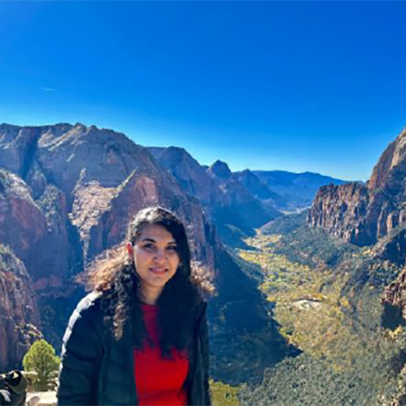 Ritty smiling at the camera with a view of mountains in the background.