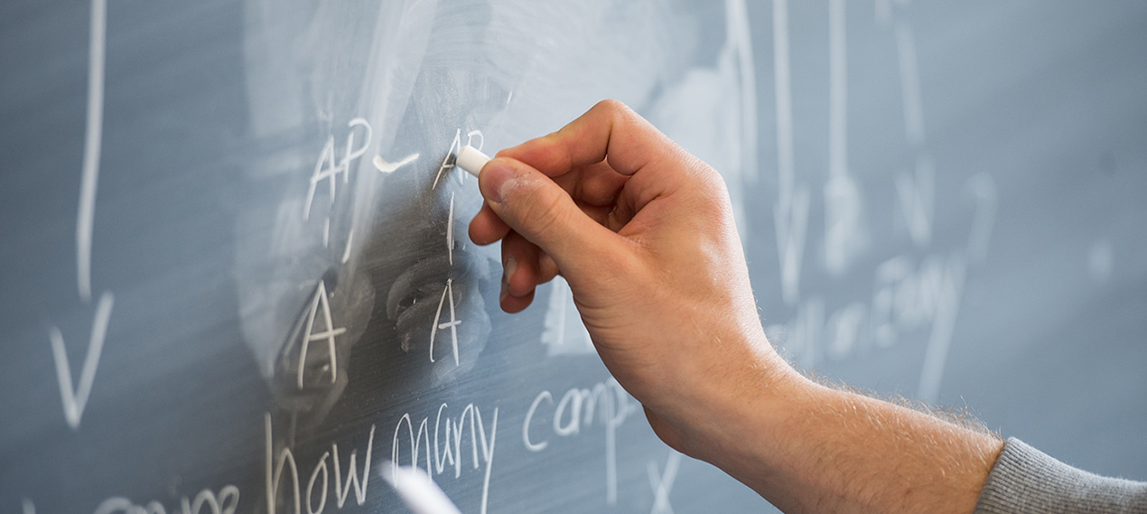 A hand writing on a blackboard.