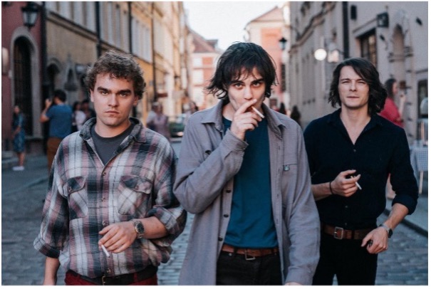 A still image from the film with three young men walking towards the camera all smoking cigarettes.