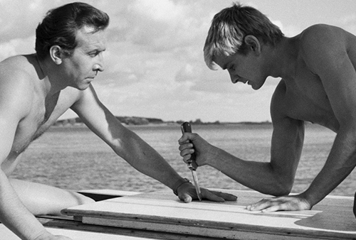 A still image from the film of two men in a confrontation on a sailboat.