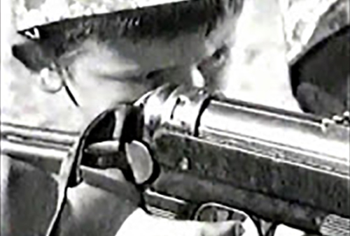 A still image from the film of a child holding a gun.