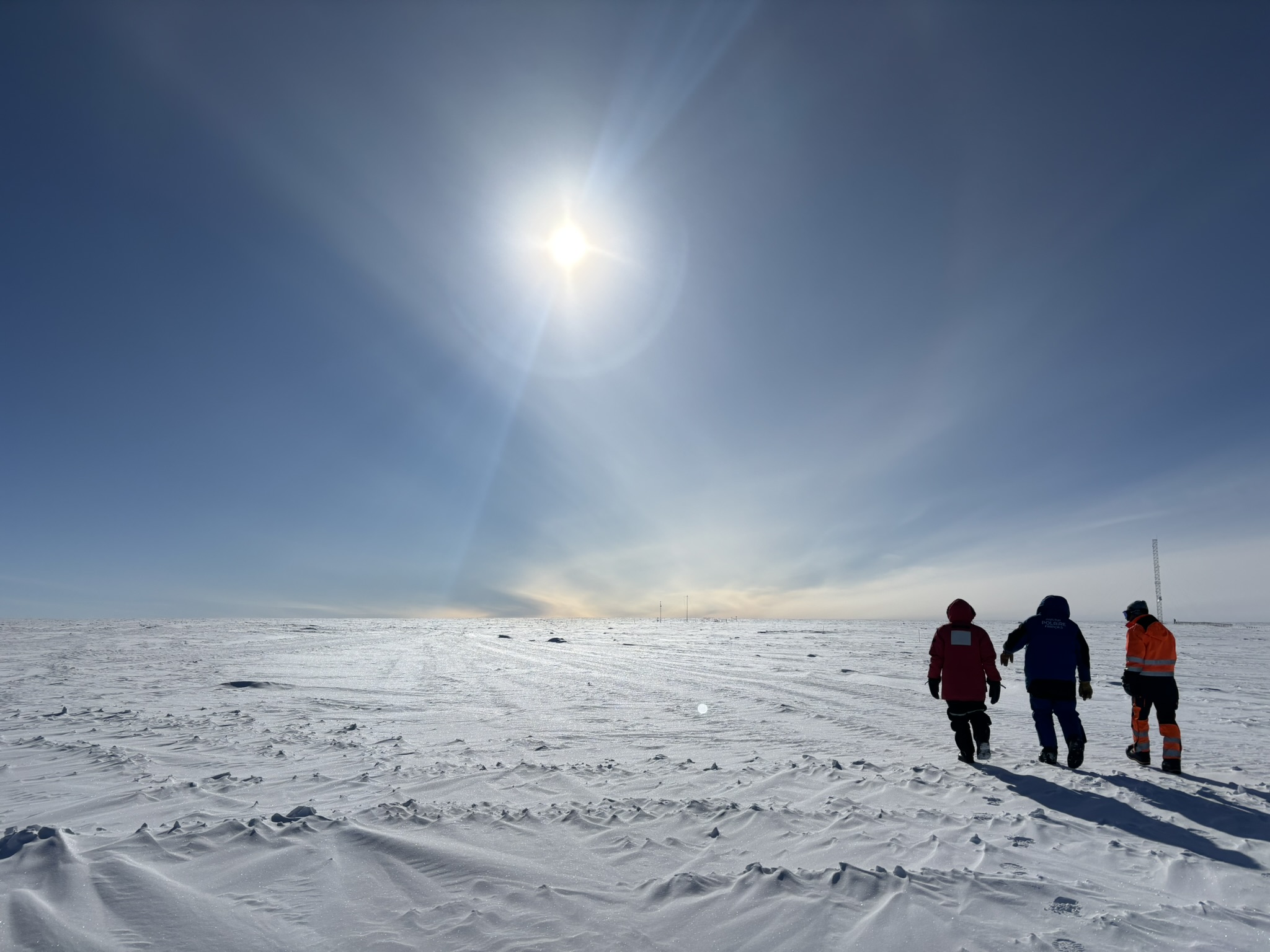 three people walking on an ice sheet