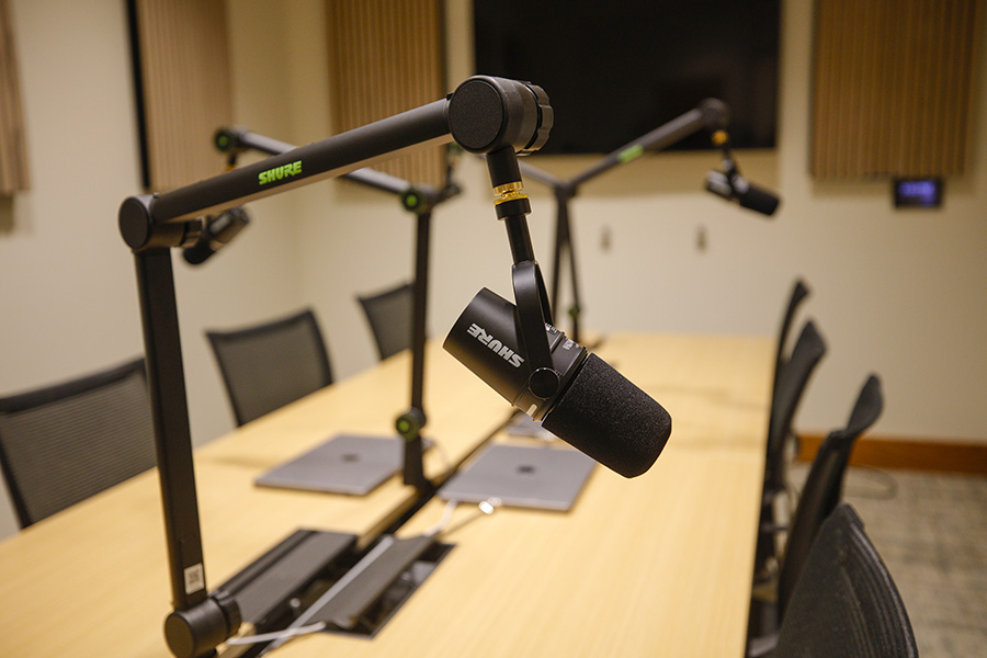 A closeup of a microphone at a desk with other microphones in the background.
