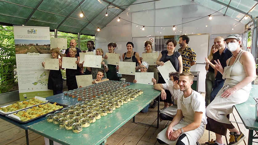 People holding certificates with a table of food in the foreground.