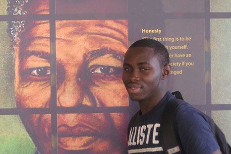 Student in front of a wall painting of Nelson Mandela and his famous quotes.