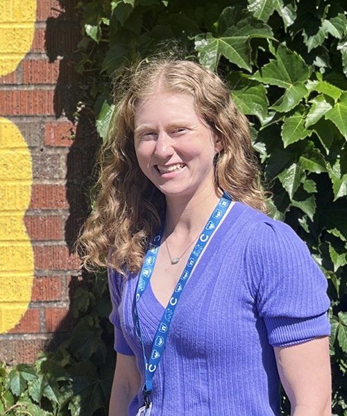 Ilana Weiss standing in front of an ivy-covered brick wall.