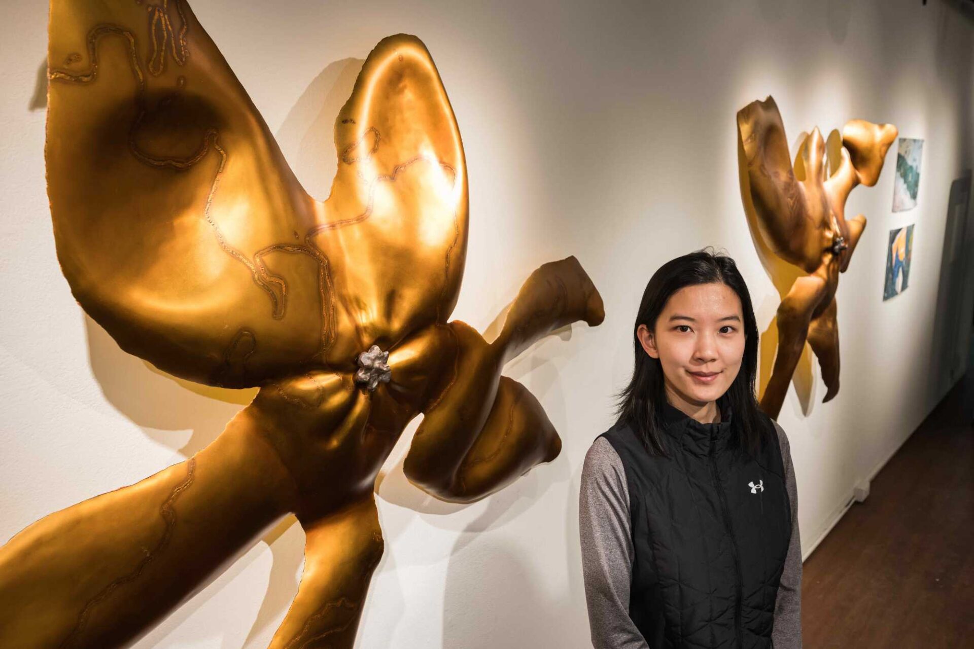 Downward angled shot of multimedia artist Renee Jin next to a sculpture exploring the concept of involution.